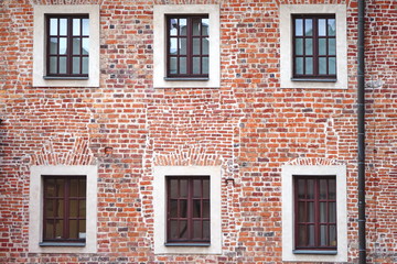 Fototapeta na wymiar The facade of an old brick building with windows or cornices. Old brick walls