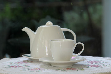 White ceramic tea set on the white wooden table.