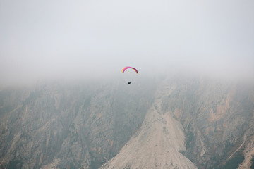 Paraglider flying over mountains in the dolomites, Italy. Sunny autumn day. - 331719070