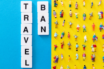 Travel ban word on a blue background and a yellow background with aligned people miniatures. Concept for the stop of banned travel and tourism. Travel forbidden due to coronavirus pandemic worldwide