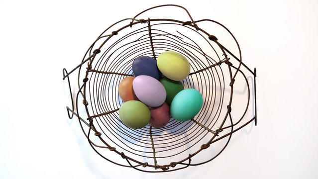 colorful easter eggs in a iron wire basket , top view. Vintage style
