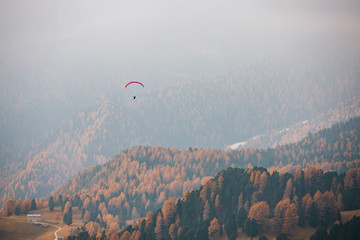 Paraglider flying over mountains in the dolomites, Italy. Sunny autumn day. - 331719213