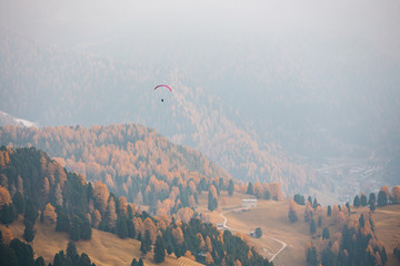 Paraglider flying over mountains in the dolomites, Italy. Sunny autumn day. - 331719232