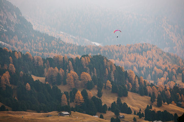 Paraglider flying over mountains in the dolomites, Italy. Sunny autumn day. - 331719238