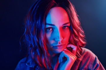 Portrait of young girl with curly hair in red and blue neon in studio