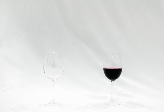 empty glass of wine with red glass of wine standing both on tne pallete with white background. Creative blank space image.