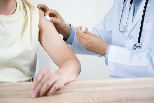 Asian man get coronavirus, flu and measles vaccine shot, vaccination in hospital for good heath, medicine injection vial dose for treatment patient. (select focus)