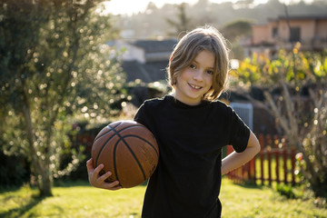 Felice bambino biondo con il pallone da basket