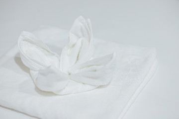 White towel folded into a flower shape put on white floor.