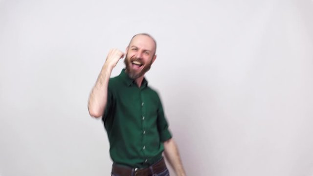 Close up of successful man celebrating a victory and raising clenched fist in the air over white background. Emotions of success, triumph, victory, winning and celebration.