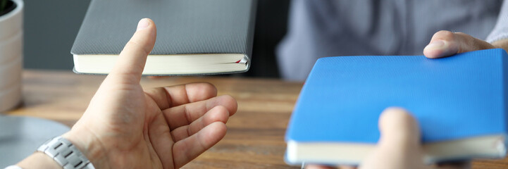 Two businessmen exchanging with notebooks at office workplace close-up