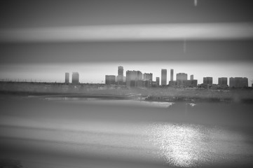 Black and white photography of city skyline. Wallpaper. Backgrounds. Sunlight reflected from the water. Print art