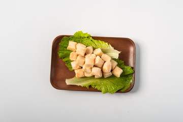 Tofu made of minced fish and crab seeds on lettuce leaves, placed in wooden plates, isolated in a white background