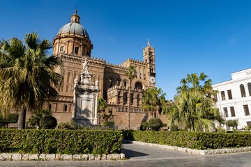 Fototapeta na wymiar The bell tower with clock and cupola of Palermo Cathedral with palm trees in Sicily