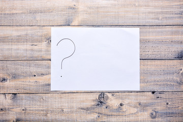 Sheet with a question mark on a wooden background