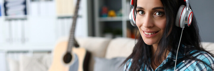 Portrait of smiling lady in modern headset playing synthesizer by notes. Lovely woman in stylish...