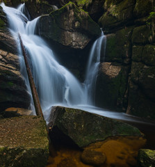 Waterfall on the black brook in the middle of spring forest. Long exposure silk flows of water.