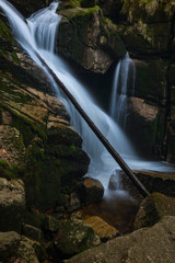 Waterfall on the black brook in the middle of spring forest. Long exposure silk flows of water.