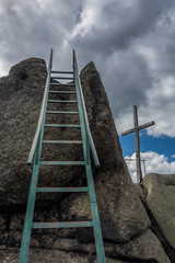 Ladder to peak of rock. Beside cross on the top.