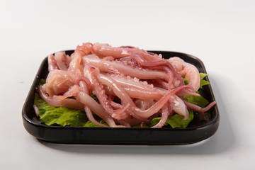 The fresh octopus is placed on the lettuce leaf, and it is placed on a black plate. On a white background, it is used as a kind of food for hotpot © InkheartX