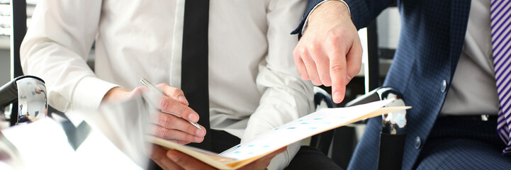 Male hand in suit and tie showing something important in tax interview document closeup