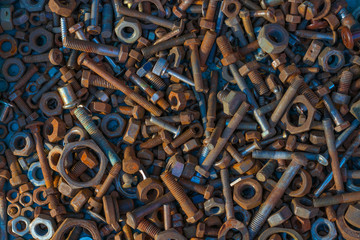 Many old rusty bolts and nuts of various sizes lie on the surface. Orange. Background or wallpaper.