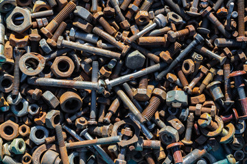 Many old rusty bolts and nuts of various sizes lie on the surface. Orange gray. Background or wallpaper.