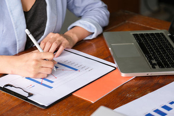 Fototapeta premium Business woman take note and write on the paper and see information from laptop. There are laptop and credit card on the table. Business, finance and technology concept.