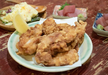 飲み会のテーブルに並んでる唐揚げとマグロの刺身とポテトサラダ