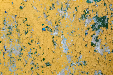 cracked yellow paint on blue concrete wall