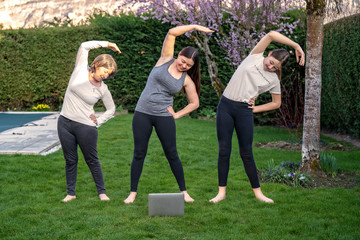 Family practicing fitness lesson online outdoors in garden at quarantine isolation period during...