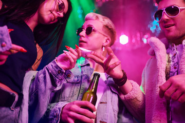 Buying drugs. Young people is having fun in night club with colorful laser lights
