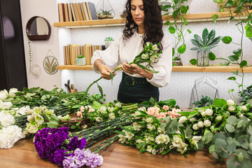 Attractive young woman florist is working in a flower shop.