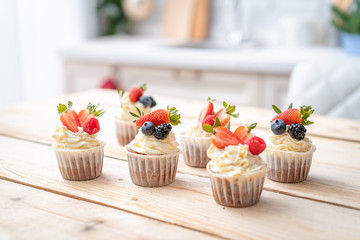 Fresh, delicious cupcakes with yogurt cream and fresh berries. Blur background.