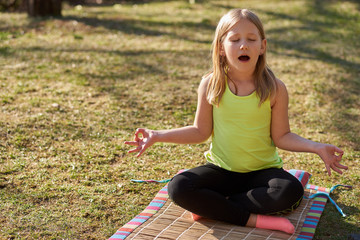 Young girl pracitcing yoga in a park during the day