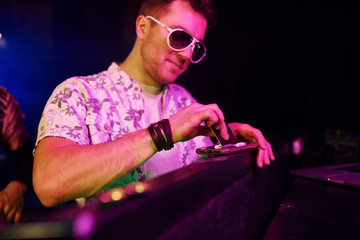 Young guy in elegant clothes and sunglasses sniffing drug in night club