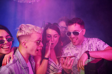 Young people sniffing drug in nightclub with colorful laser lights