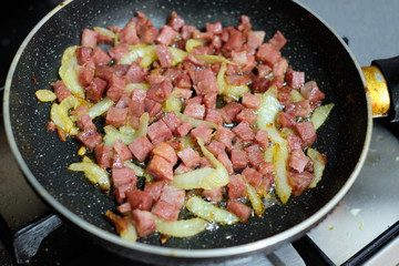 Ham with onion frying in frying pan