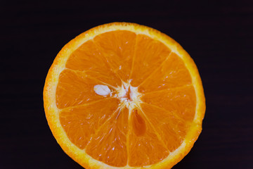 Top-view close-up orange half on the dark wooden table. Fresh citrus fruit slice.