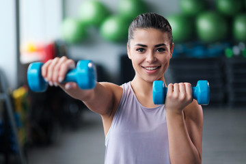 A beautiful athletic young brunette woman in sportswear trains in the gym.