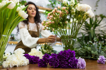 Attractive young woman florist is working in a flower shop.