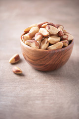 Brazil nuts in wooden bowl on wood textured background. Copy space. Superfood, vegan, vegetarian food concept. Macro of brazil nut texture, selective focus. Healthy snack.