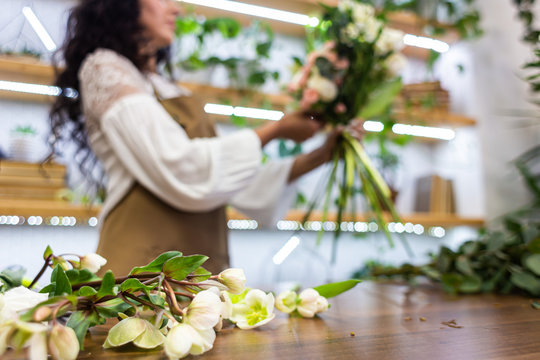 Attractive young woman florist is working in a flower shop.