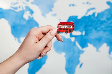 Fotobehang Travel concept. Watercolor illustration of London red bus with text "I love London" in a woman's hand. Background world map watercolor illustration © Liudmyla
