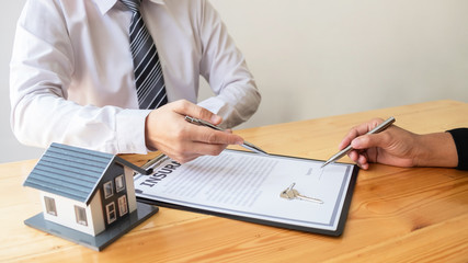Agent is advising clients to sign a contract for home insurance in the office.