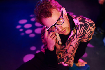 Young man in glasses have fun inside of night club with pink lightings