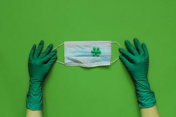 Medical mask in doctors hands with protective gloves. Green background. Coronavirus concept. Pandemic in the world.