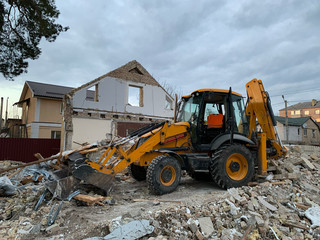 Ruined, brick, residential building. The ruins of a collapsed mansion in the forest. Demolition of an old house with an excavator. The destroyed walls of the building.