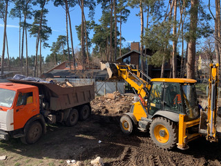 Heavy equipment near the destroyed brick house. Construction machinery on the background of the...