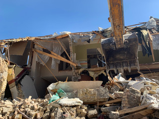 Heavy equipment near the destroyed brick house. Construction machinery on the background of the...